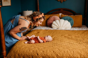 mother leaning over bed tickling her baby's toes