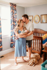 mother and father holding baby in nursery